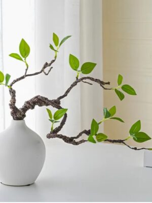 กิ่งไม้ฟิกัสเทียมที่เหมือนจริงในแจกันเซรามิกสีขาว